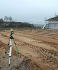 Outdoor construction site with a Beast Dual-Slope Grade Laser Level Kit With HL760 Meter, tripod setup on rough terrain.