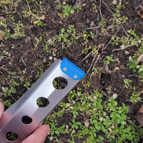 Ultralight Backpacking Trowel 0.48 Oz 13.5 G Blue With Lifetime Warranty Made In USA in use on soil with blue end cap visible.