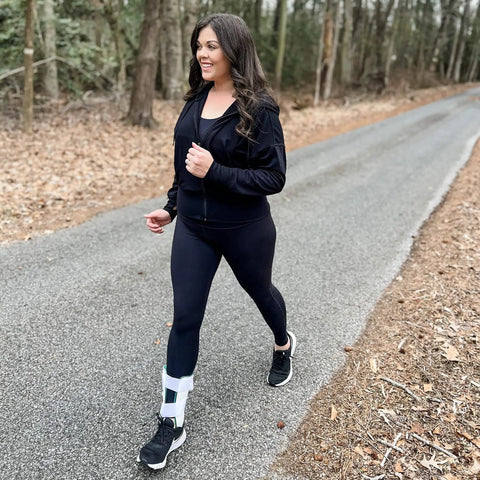 Person walking on path wearing Air Gel Ankle Stirrup Brace With Customizable Air And Gel Support And Cold Therapy For Targeted Stabilization And Pain Relief One Size Fits All For All Day Comfort