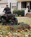 Rear view of ATV towing Beast Of A Tow Behind Landscape Rake For ATV And UTV 48 Inch Wide With 2 Inch Receiver 17 Heavy Duty Spring Steel Tines