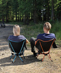 Two people sitting on Ultra Lightweight Folding Camping Chairs For Outdoor Adventures and Travel in a forest area