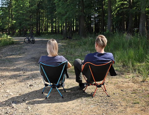 Two people sitting on Ultra Lightweight Folding Camping Chairs For Outdoor Adventures and Travel in a forest area