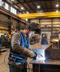 Air Compressed Cooling Vest For Industrial Crews Featuring Vortex Tube Tech worn by worker welding in busy steel mill.