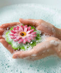 Flower Power Bathtub Drain Stopper With Chain Pink Green Universal 4 1 4 Inch Bath Plug in hands filled with bubbles.