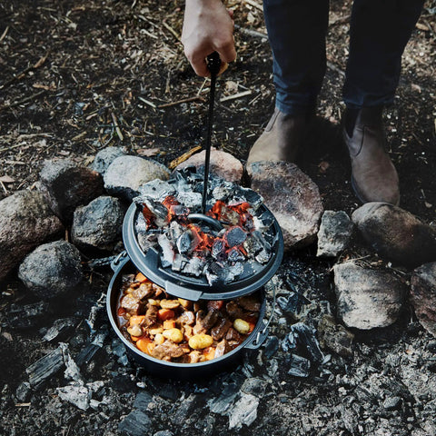 Cooking stew in Six Quart Cast Iron Camping Dutch Oven With Lid Lifter And Storage Bag For Campfire Cooking Stews And Baking Durable Pre Seasoned Outdoor Pot For Camping And Hiking over campfire