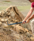 Person using Geo Paleo Rock Pick 25 Inch USA Made Geologist Tool With All Steel Construction And Vinyl Cushion Grip on rocks