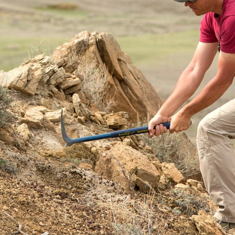 Person using Geo Paleo Rock Pick 25 Inch USA Made Geologist Tool With All Steel Construction And Vinyl Cushion Grip on rocks