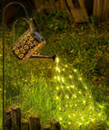 Copper Solar Watering Can Garden Light With Waterfall Effect And 60 LEDs illuminating grass in a yard at night.