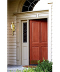 One Light Exterior Wall Lantern In Polished Brass Finish With Clear Beveled Glass For Crisp Outdoor Porch Lighting, 18.5 In High By 5.75 In Wide, Extends 6 In, 11.5 In Center Of Outlet Box Height, Back Plate 4.5 In installed beside a red door