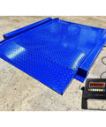 Heavy Duty Low Profile Drum Scale Built Tough With Smooth Hinged Ramps For No Sweat Barrel Rolling And Rock Solid Weighing Capability Up To 5000 Pounds With Spot On One Pound Accuracy NTEP Approved, blue steel platform with digital display.