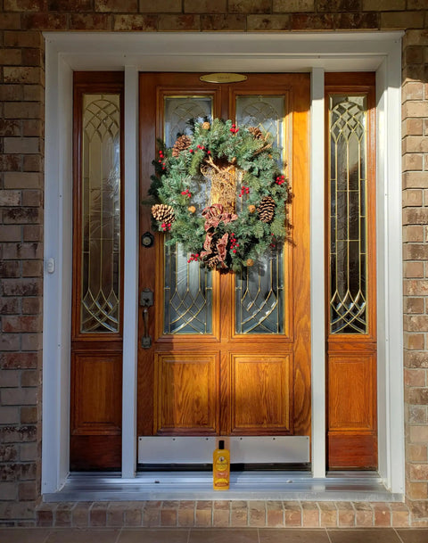 Front door decorated with wreath; Sun Shield Wood Wax With UV Protection For Outdoor Furniture Gallon placed below.