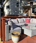 Outdoor deck with wicker furniture, red railing, and solar lights in a residential backyard setting.