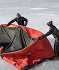 Two men setting up Quickfish Six Person Portable Pop Up Ice Fishing Shelter With Fully Quilted Insulation No Trip Door And Deluxe Anchors For Hell Of A Winter Setup In Red Black on ice.