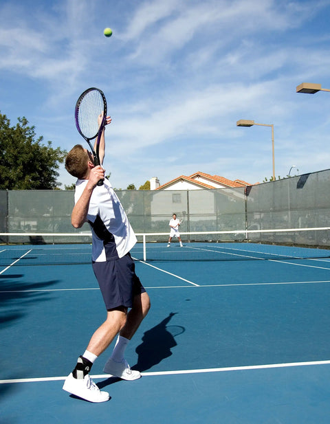 Tennis player wearing A60 Ankle Support Brace For Right Foot White Medium With Side Stabilizers Molded At Sixty Degree on court