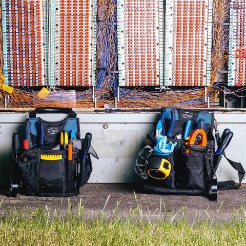 Two Pro Grade Heavy Duty Utility Pouches with multiple pockets and 59 inch belts on grass in front of electrical panel.