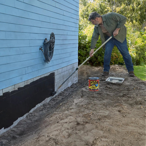 Man applying 1-gallon Liquid Rubber Sealant Coating for waterproof, flexible protection on house foundation with brush roll tool.