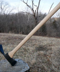 Pulaski Style Wildfire Axe With 3.75 Lb Forged Steel Head And 36 Inch Hickory Handle displayed on a tree stump in forest setting.