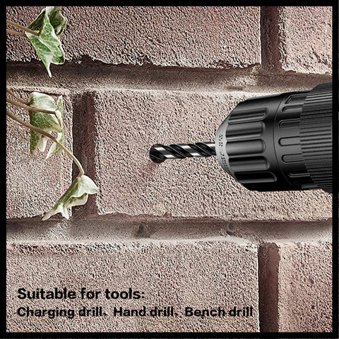 Side view of a black cordless drill with a masonry bit drilling into a brick wall; plant leaves visible left