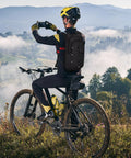Cyclist wearing Lightweight Hydration Backpack With 2L Water Bladder, breathable mesh straps, black, in mountain landscape