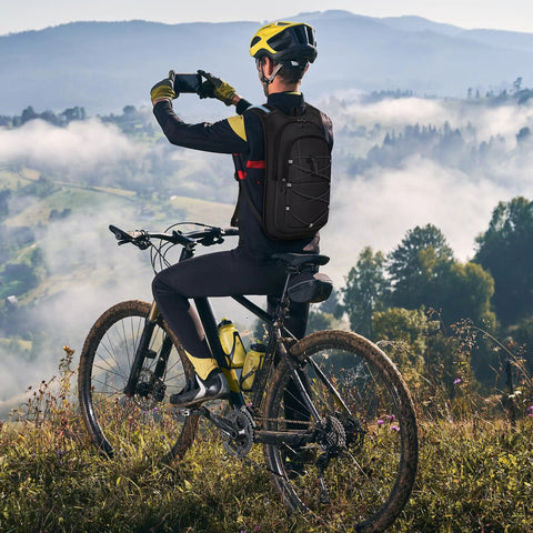 Cyclist wearing Lightweight Hydration Backpack With 2L Water Bladder, breathable mesh straps, black, in mountain landscape