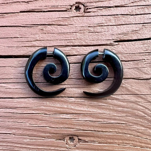 Spiral Fake Gauge Earrings Set In Black With Organic Wood And 316L Surgical Steel displayed on wooden surface