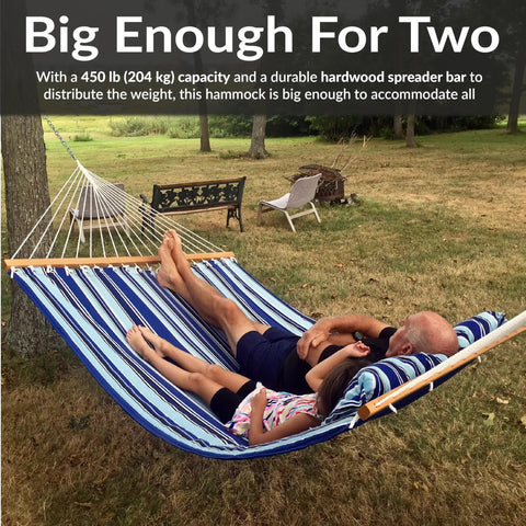 Two people relaxing on a Quilted Double Outdoor Hammock With Spreader Bars 74x55 Inch Bed 450 Lb Capacity set up in a yard