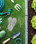 100 Pack Drip Irrigation Staples, J Shape Garden Stakes, 5 Inch Lawn Pins for Securing Half Inch Drip Tubing, Landscaping Stakes for Outdoor Garden displayed with garden tools on grass