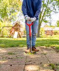 Person using Manual Serrated Garden Edger for Landscaping and Clean Lawn Borders, Steel Tool in Red, Half Moon Blade with Inverted V Cutting