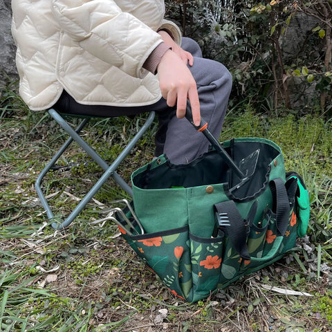 Person sitting on a Foldable Gardening Stool With Detachable Storage Tote For Gardening Camping And Fishing Tools Organizer Portable Garden Chair For Adults With Sturdy Steel Frame And Easy Grab And Go Carry Design