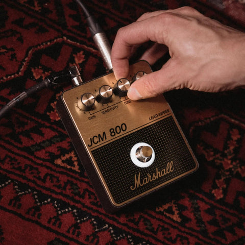 Hand adjusting controls on JCM800 Inspired Overdrive Distortion Guitar Pedal With Gain Sensitivity And Tone Controls Black And Gold Finish