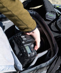 Person accessing camera inside Rotating 50L Plus Camera Backpack For Epic Adventure Photography With Front Access, Tripod Carry