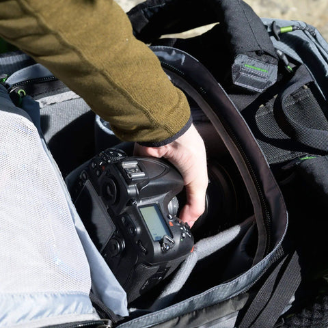 Person accessing camera inside Rotating 50L Plus Camera Backpack For Epic Adventure Photography With Front Access, Tripod Carry
