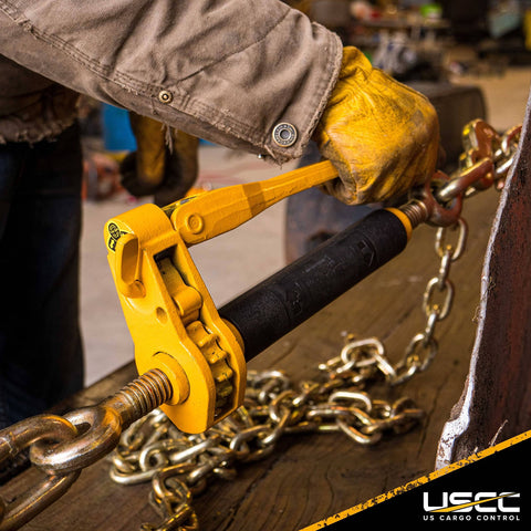 QuikBinder Plus Ratchet Load Binder For Grade 70 And Grade 80 Chain Five Sixteenths To Three Eighths Inch With Folding Handle And 7100 Lbs Working Load Limit Heavy Duty Chain Binder For Secure Trailers Equipment And Towing in use securing chain on trailer with yellow handle.