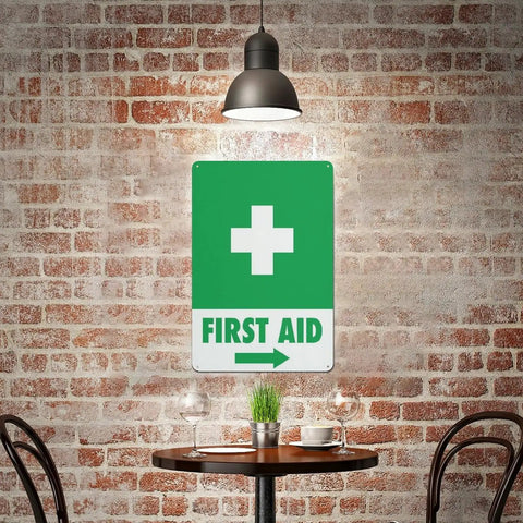 Right Arrow Green First Aid Sign 8x12 Inches Weatherproof Reflective Aluminum Plate on brick wall in cafe setting.