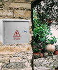 Weatherproof Outdoor Electrical Junction Box 300x400x160mm installed on stone wall, heavy duty iron enclosure for power control.