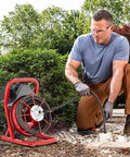 Heavy Duty Electric Drain Snake Cleaner With 75 Foot Steel Core Cable And 400W Motor in use outdoors, clearing a blockage.