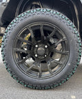 Rugged Four Seater Electric Golf Cart With Powerful Ac Motor Built To Crush Hills and Deliver Whisper Quiet Ride featuring black alloy wheel and all-terrain tire.