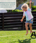 Child balancing on Backyard Slackline Kit Freestanding Slackline System For Kids And Adults in sunny backyard