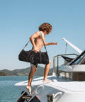 Person carrying 90L Large Mesh Duffle Bag For Scuba Gear Snorkel Equipment And Water Sports Adventure on a boat under clear sky.