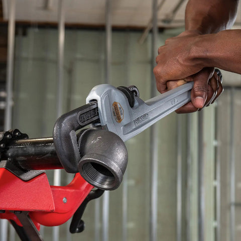 Ultra Lightweight Aluminum 18 Inch Pipe Wrench With I Beam Handle used by a person to adjust a pipe fitting