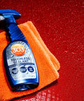Touchless SiO2 Shield Sealant bottle on orange cloth, red glossy background, water beading effect, 1 gallon refill for trigger bottle