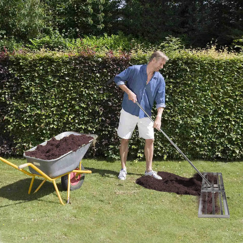 Man using Stainless Steel Lawn Level Tool With Handle For Leveling Soil And Lawn In Garden Backyard And Golf Courses Durable 7Ft Ground Leveler 30x10In For No Sweat Fast Even Turf next to wheelbarrow on grass