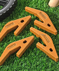4 Piece Backhoe Bucket Teeth Adapter Set For U43792 Series Excavators And Skid Steers displayed on grass