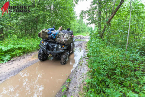 ATV on a muddy trail carrying luggage secured with Heavy Duty Bungee Cord Set Of 12 With Double J Hooks, 32 Inch Elastic Straps
