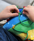 Child interacting with a Colorful Buckle Pillow Sensory Toy For Fine Motor Development And Kid Friendly Hands On OT Therapy With Threading Counting Latches And Zipper Skill Practice SENSORY4U Plushie.