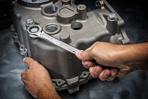 Hands using Ratcheting 12 Point Combination Wrench 1 5/8 Inch With 72-Tooth Box End on machinery bolt in tight space