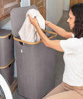 Woman using Breathable Fabric Laundry Hamper With Lid, Bamboo Frame, Side Handles, 26 Gallon Gray Go-To Laundry Basket in laundry room