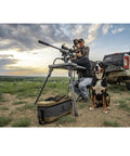Stable Table Lite With Weatherproof Tabletop And Ambidextrous Seat used for shooting next to a truck and dog in an open field.