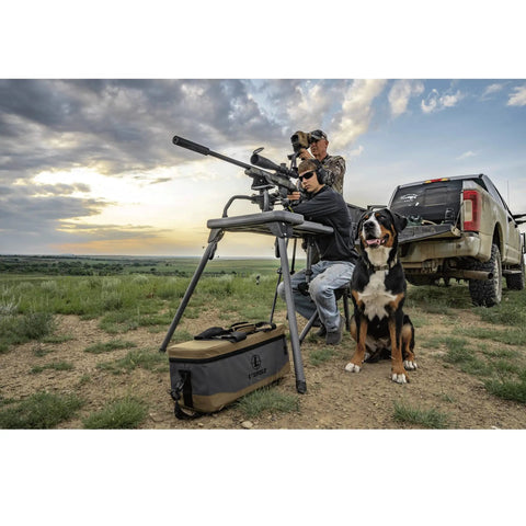 Stable Table Lite With Weatherproof Tabletop And Ambidextrous Seat used for shooting next to a truck and dog in an open field.