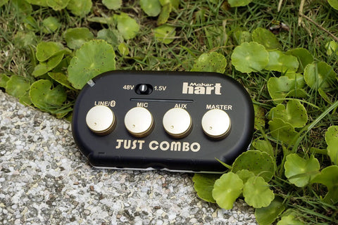 Just Combo Podcast Mini 3 Channel Audio Mixer lying on grass with visible control knobs for Line, Mic, Aux, Master settings.